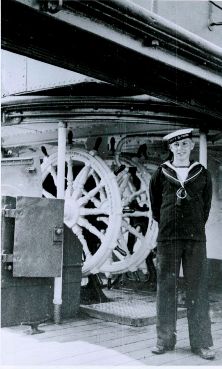 Sailor Standing by HMCS Rainbow's Wheel 