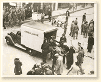 Des victimes sont places dans une ambulance par des engags de la dfense passive aprs un raid de bombardement allemand sur la ville d'East Anglia, Angleterre, 1940. Rfrences photographiques : Acme Newspictures Inc.