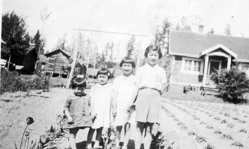 Image of four sisters standing in front of home