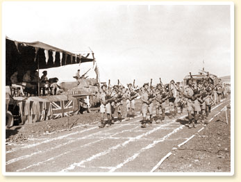 The pipers of the 48th Highlanders of Canada, an infantry unit from Toronto, Ont., entertain at a Canadian Army track and field meet during a rest period in the battle for Sicily, 23 August 1943. - Canadian Military Photograph, No 23196, CWM Reference Photo Collection