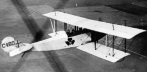 A biplane flies above a farm.