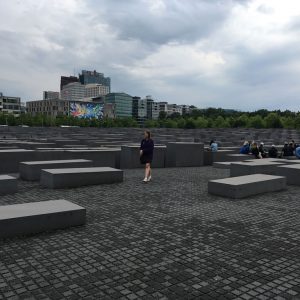 A girl walks among a field of large, grey stone blocks