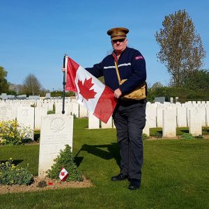 A man with a Canadian flag in a cemetery