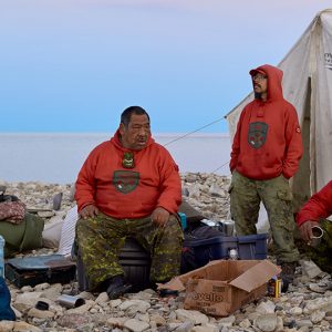 A group of people sitting in front of a tent up North.