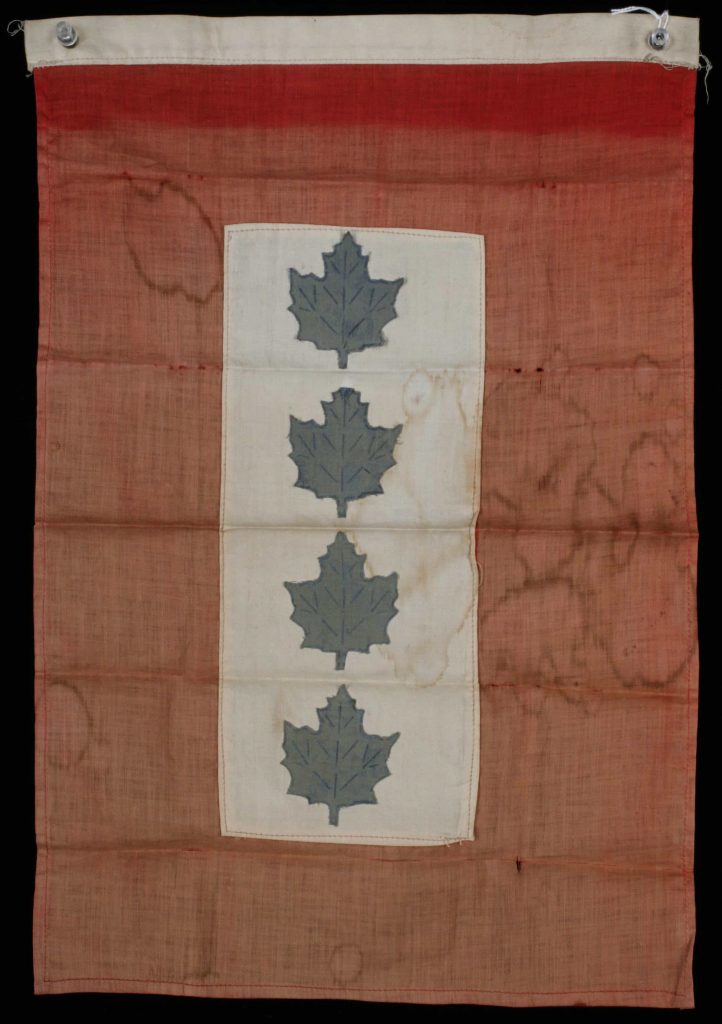 A faded red flag, with a central white patch adorned with four blue maple leaves