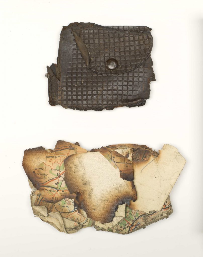 A damaged change purse and pieces of a charred map