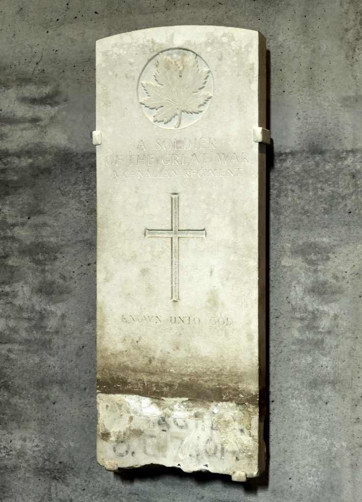 A stone tombstone decorated with a maple leaf and a cross, and the inscription: A Soldier of the Great War - A Canadian Regiment - Known Unto God