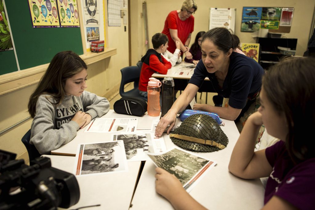 Students looking at artifacts in classroom with their teacher
