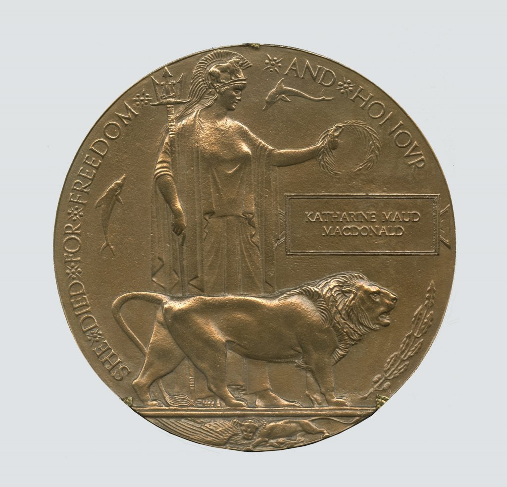 A bronze disc engraved with the Britannia figure holding an olive wreath and a trident, and accompanied by a lion and two dolphins. The figures are encircled with the words “She died for freedom and honour”. Katherine Maud Macdonald’s name is inscribed on the right-hand side.
