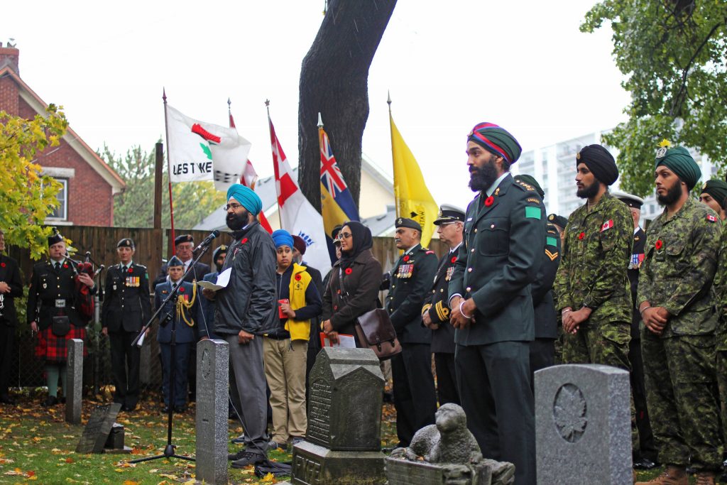 A ceremony in a cemetery, attended by Sikh military personnel and others.