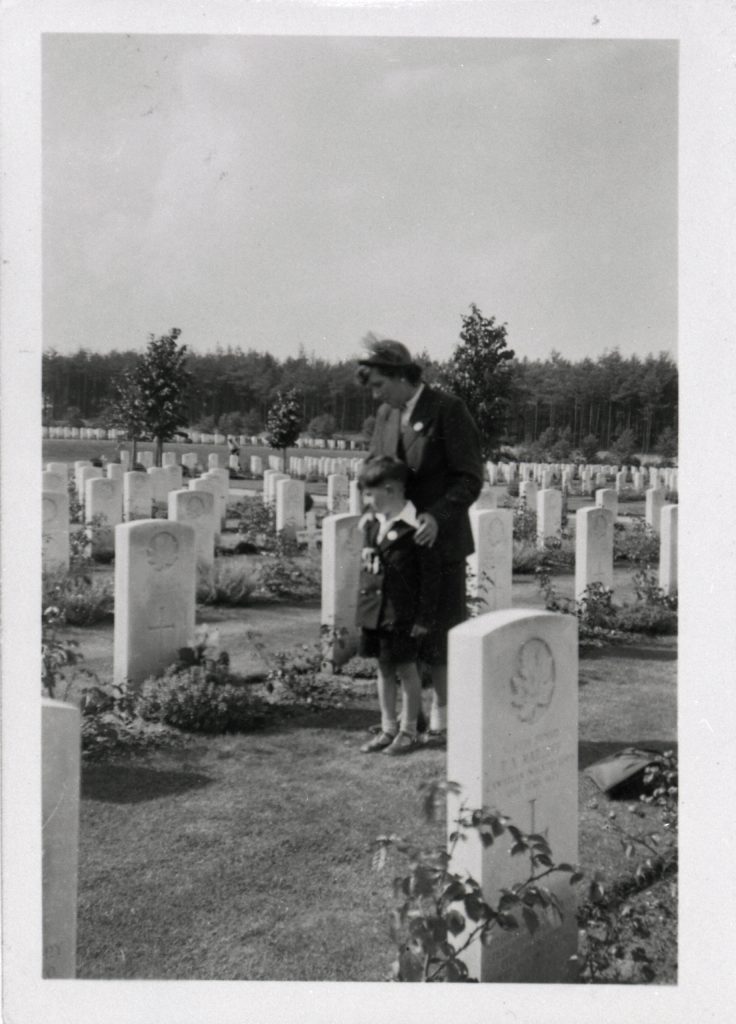 Lily and young Donald Worden, dressed in their best attire, gaze down at the tombstone of Edwin Worden.