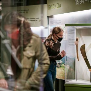 A young girl looks carefully at a machete in a display case.