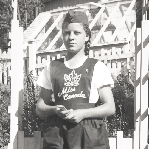 A girl in an apron standing in front of a fence at the Canadian War Museum in Ottawa.