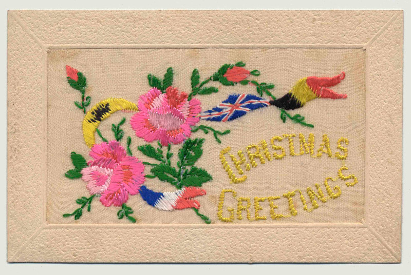 A rectangular piece of embroidery showing colourful flowers, green leaves, and the French and British flags, beside yellow text reading “Christmas Greetings.”