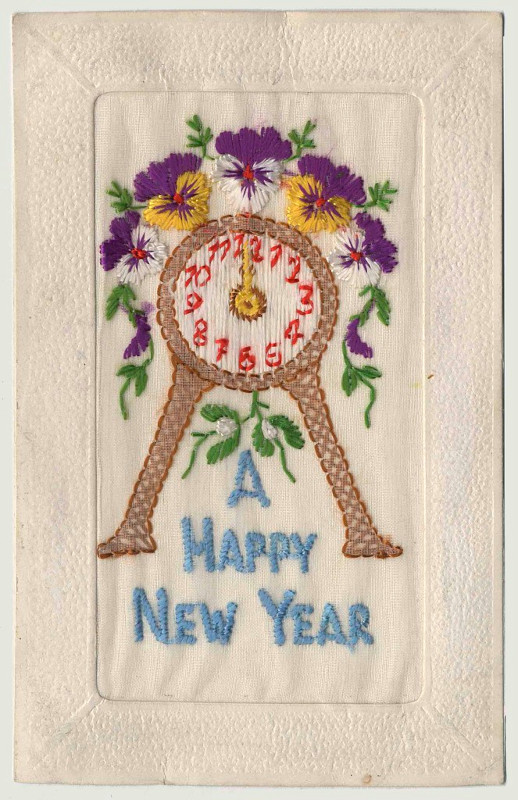 A rectangular piece of embroidery showing a clock surrounded by purple flowers above blue text reading “A Happy New Year.”