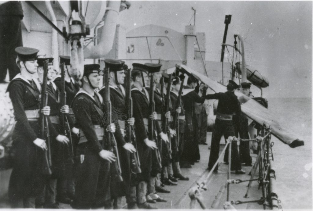 A group of men in uniform standing on the deck of a ship at the Canadian War Museum in Ottawa.