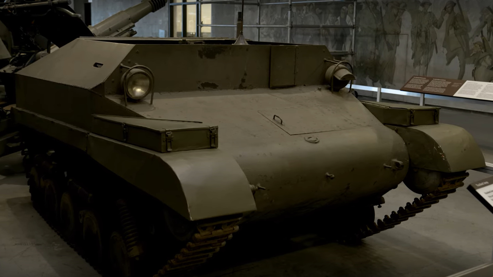 A low, dark green metal vehicle with narrow tracked treads, covered with armour plating.