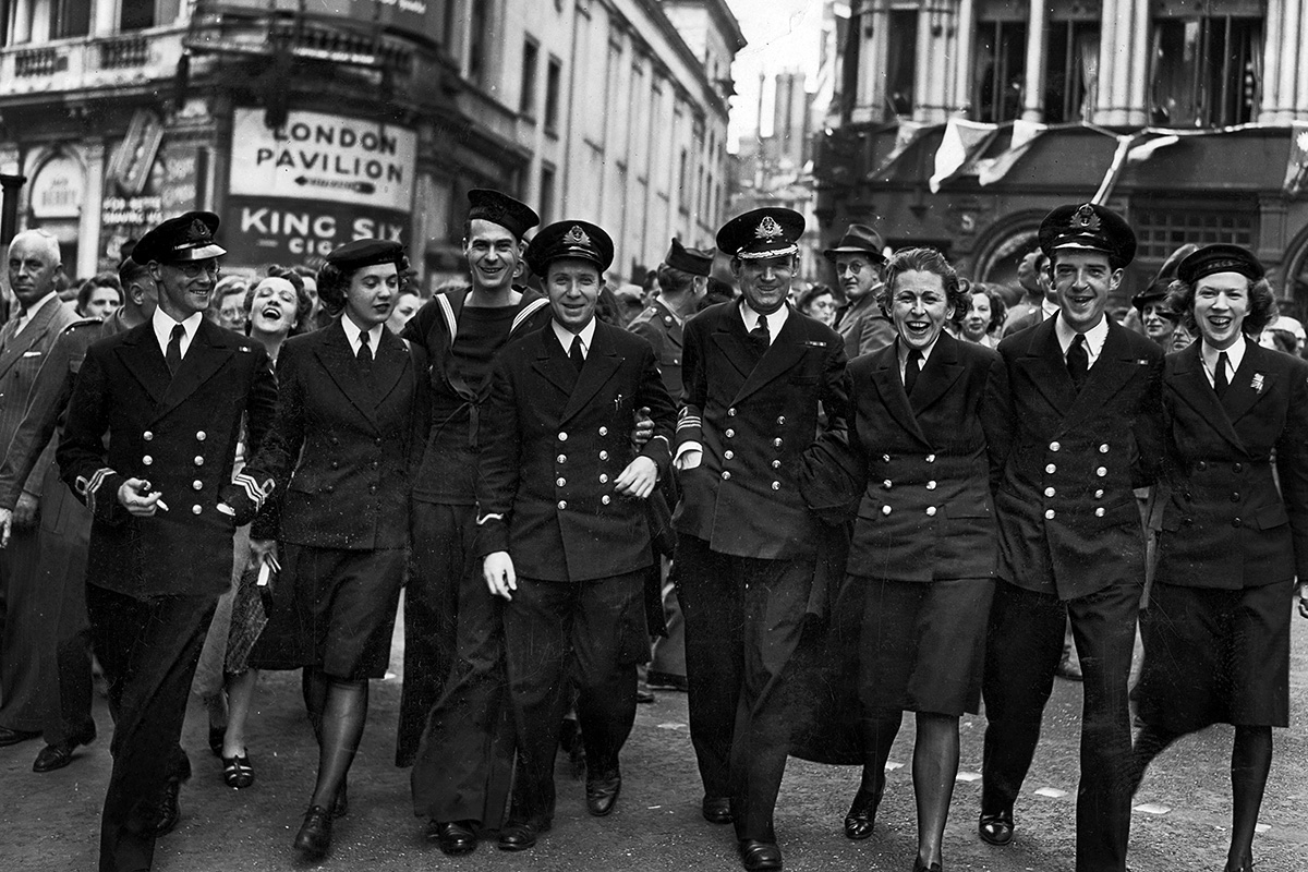 Photograph of a group of smiling service personnel walking in a wide line towards the camera.