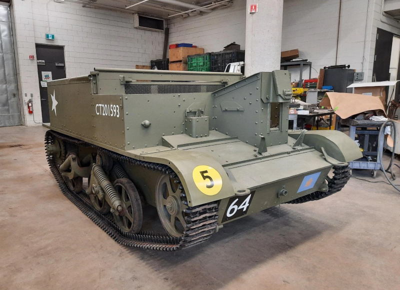 The same boxy armored vehicle with its drive wheels and tracks re-installed, looking pristine in dark green paint and painted with various identifying numbers, letters and symbols.