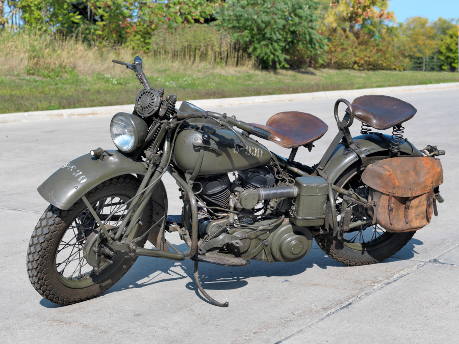 A dark green motorcycle with two large brown seats and a soft leather pannier.