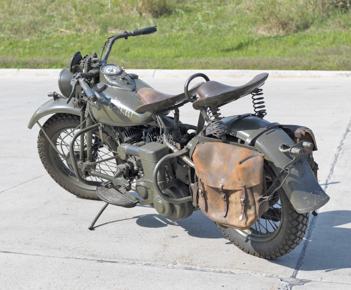 A dark green motorcycle with two large brown seats and a soft leather pannier.