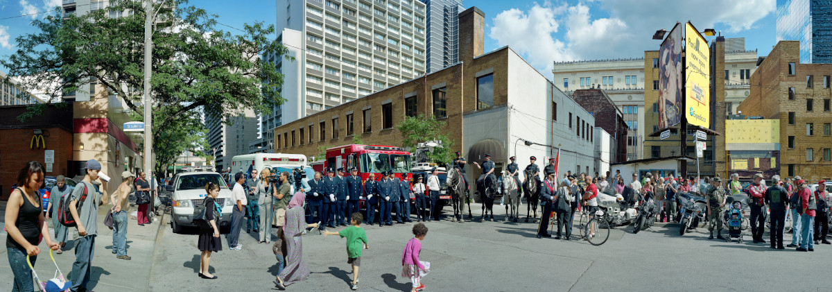 A panoramic photo of a downtown intersection lined with people in uniform, saluting.