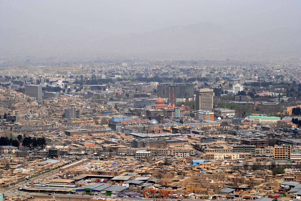 A diverse cityscape fills the frame, including large areas of low buildings, groups of apartment buildings, some official and religious structures, and treed areas.