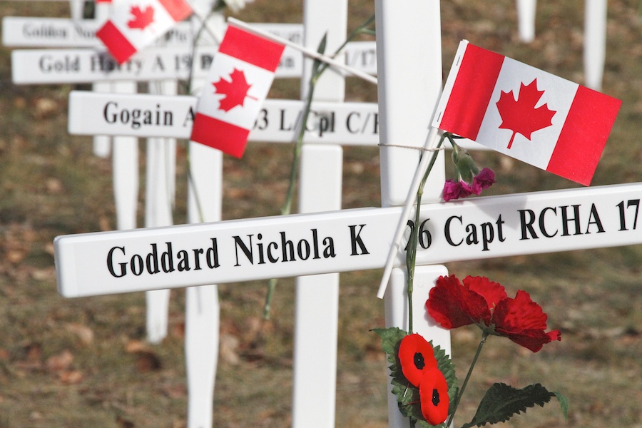 A row of white crosses decorated with poppies and small Canadian flags. The first reads “Goddards Nichola K 26 Capt RCHA 17.”