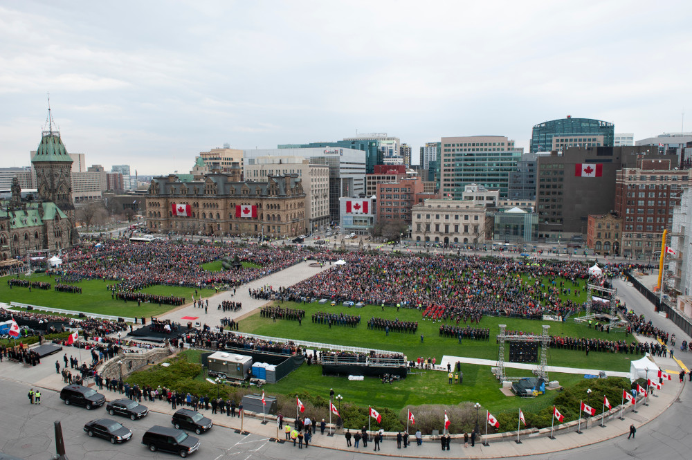 View from a height showing large crowds of people filling the lawn of Canada’s Parliament Hill.